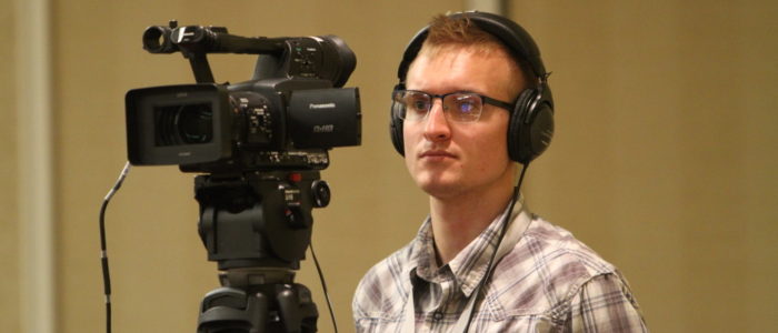 man with headphones behind a camera